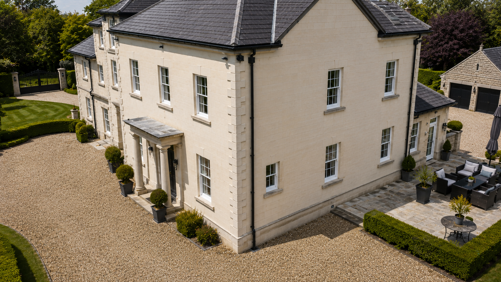 Aerial view of a substantial detached house with terracotta tiled roof, orange brick elevations, multiple gables and a block paved driveway